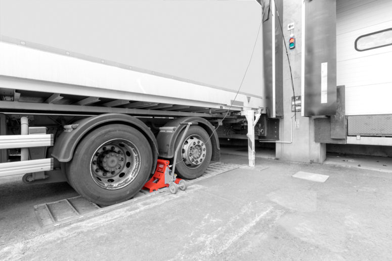 Wheel chock POWERCHOCK set in front of rear wheel of trailer to block vehicle at loading dock
