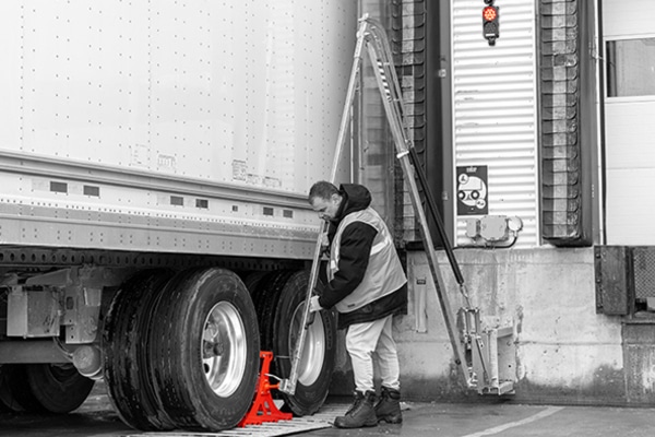 Driver is setting up the POWER CHOCK® 5 wheel-based vehicle restraint in front of the rear wheel of the truck