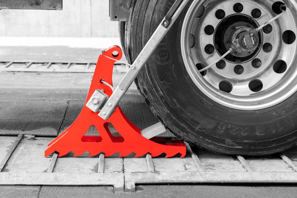 Side and close view of the POWER CHOCK 5 effectively restraining the wheel of the trailer at the loading dock.